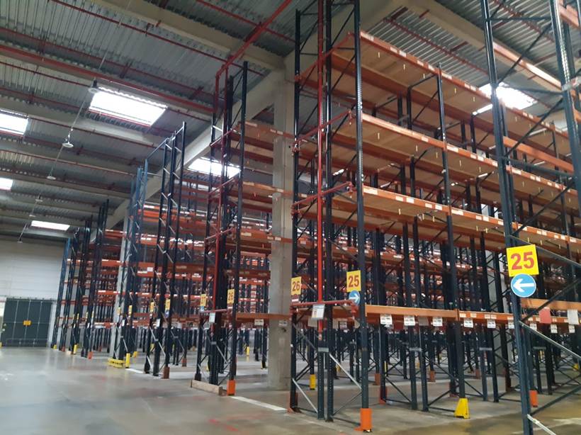 Allées de racks à palettes numérotées dans un entrepôt logistique avant intervention de rachat et démontage